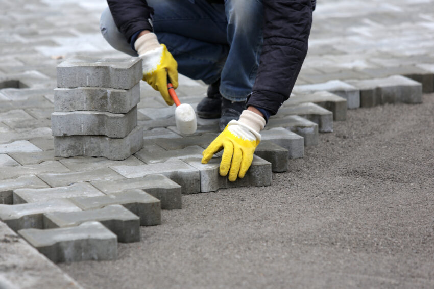 Man laying an outdoor patio in the winter months.