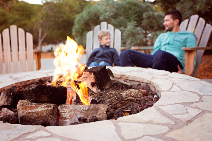 A man and a boy behind an outdoor firepit on a patio in the winter.