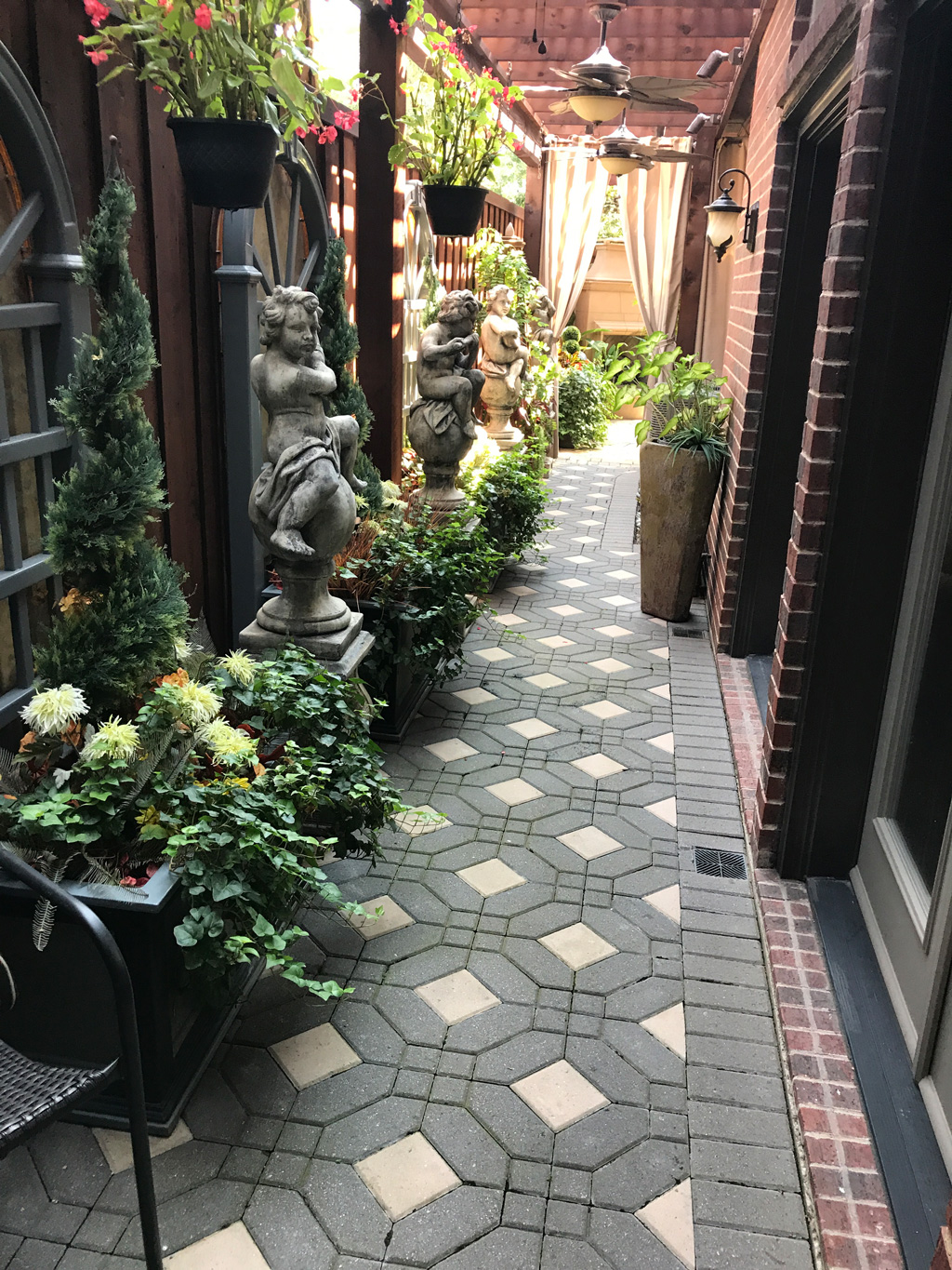 Paved side yard with plants and statues to show how to make the most of a small backyard.