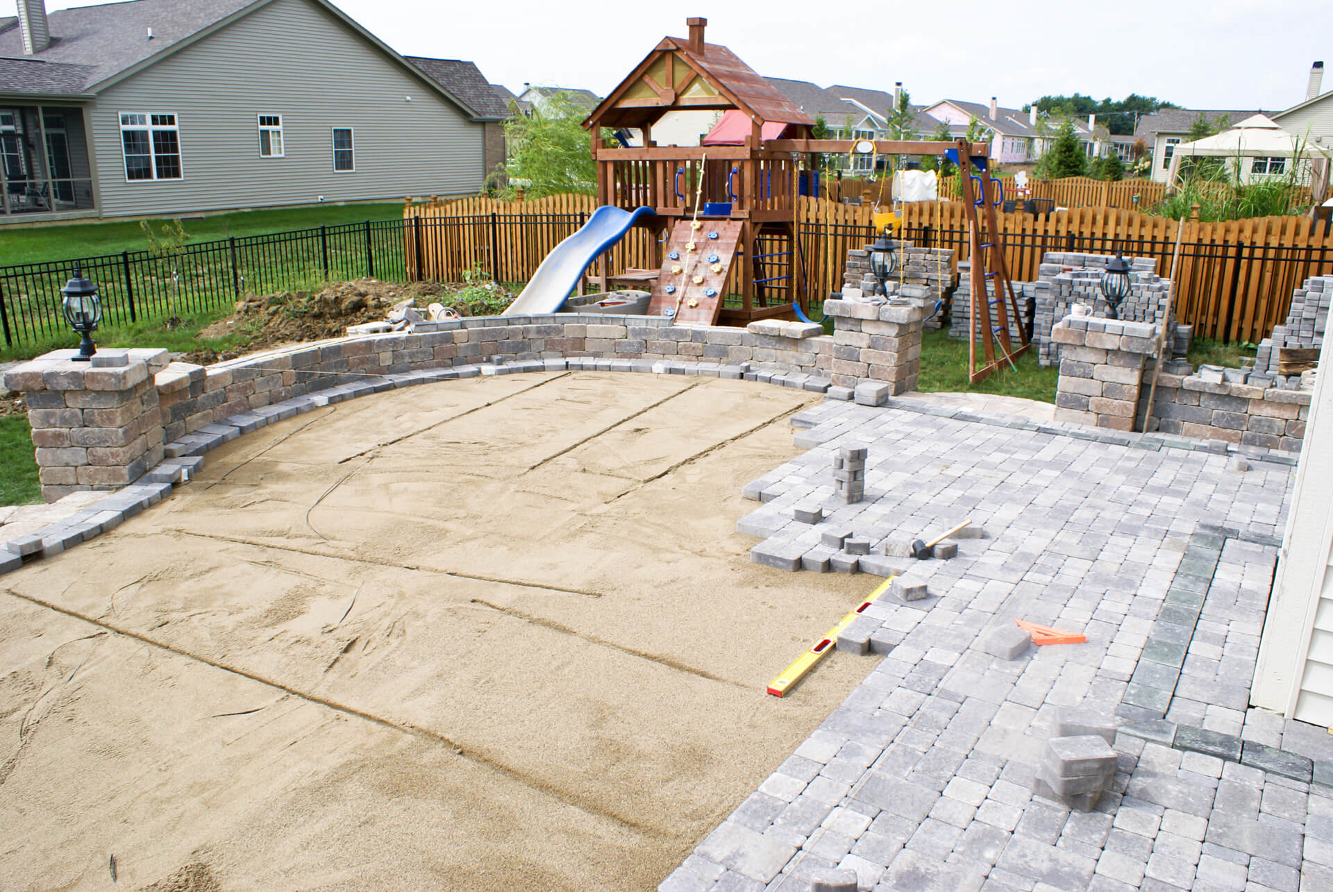 Paved backyard patio with outdoor activities for toddlers like a playground